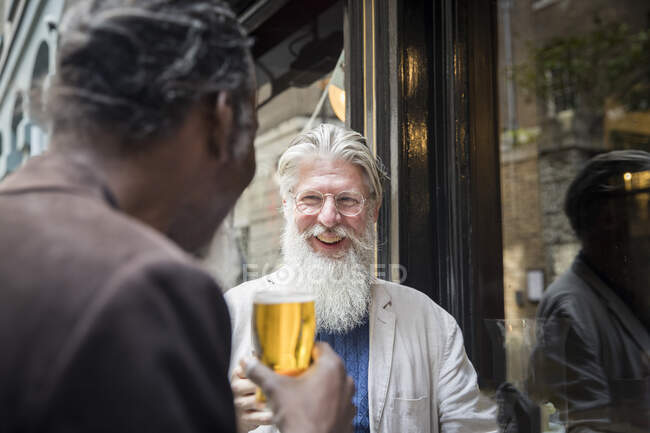 Two mature men, standing outside pub, drinking beer — Stock Photo