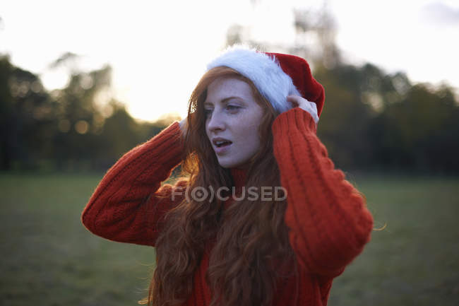 Jovem mulher vestindo em chapéu de Santa em ambiente rural — Fotografia de Stock