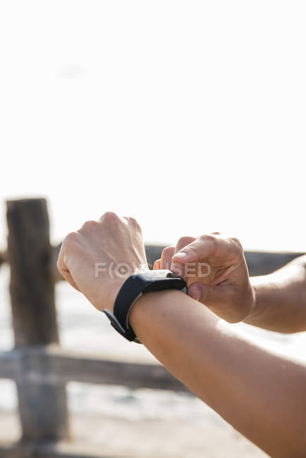 Junge Frau beim Training am Meeresufer beim Anblick einer Smartwatch, Hände in Großaufnahme — Stockfoto