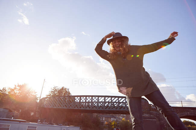 Woman balancing by canal, bridge in background — Stock Photo