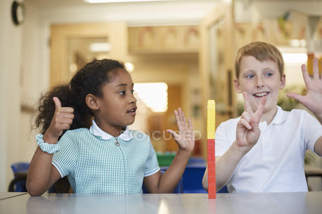 Colegial y niña contando con los dedos en el aula en la escuela primaria - foto de stock