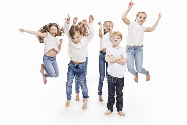 Estúdio retrato de dois meninos e quatro meninas se divertindo pulando no ar, comprimento total — Fotografia de Stock