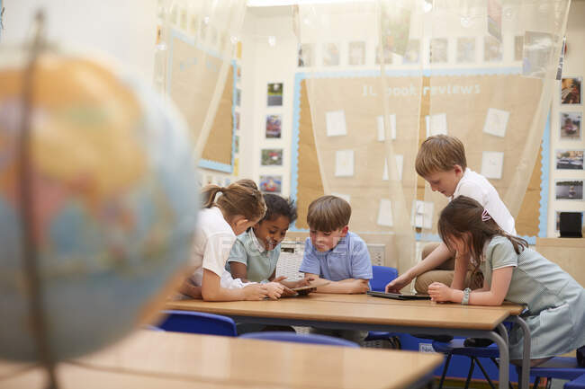 Школярки і хлопчики дивляться на цифрові планшети в класі уроки в початковій школі — стокове фото