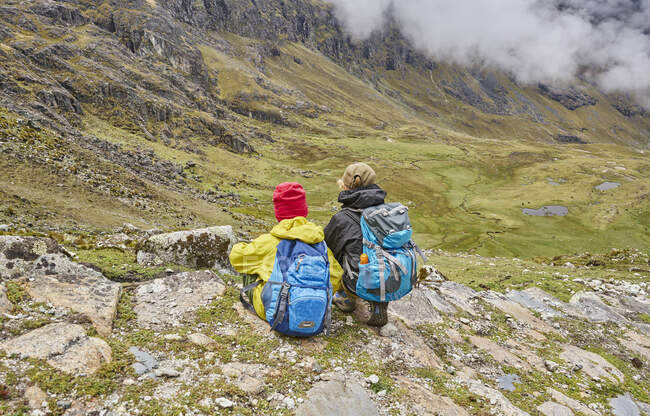Двоє хлопців сидять на схилі пагорба, дивлячись на вид, задній вид, Вентілья, Ла - Пас, Болівія, Південна Америка. — стокове фото