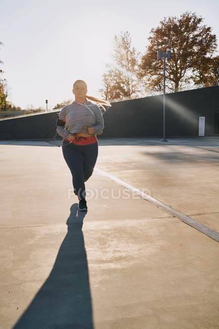 Изогнутая молодая бегунья, бегущая под солнцем — стоковое фото