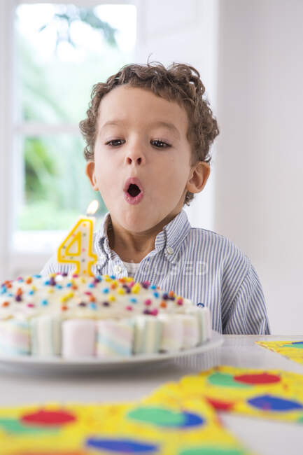 Portrait of boy blowing out candle on cake — Stock Photo