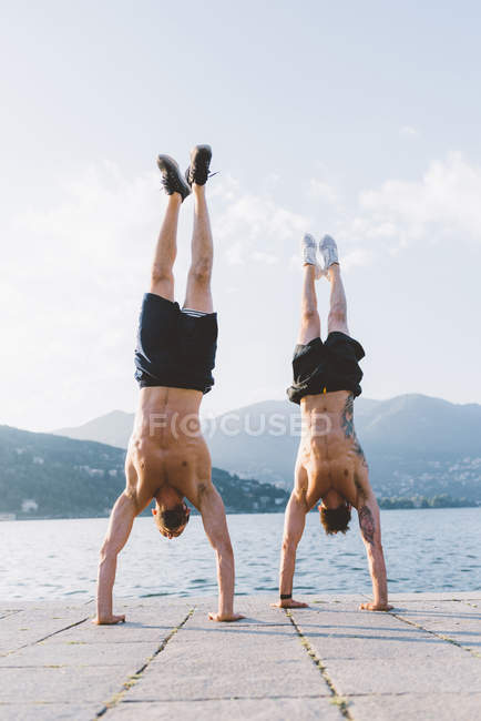 Dois jovens fazendo suportes em beira-mar, Lago de Como, Lombardia, Itália — Fotografia de Stock