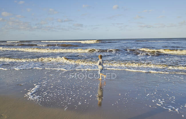 Мальчик на пляже играет в круговых волнах, Полонио, Роча, Уругвай, Южная Америка — стоковое фото