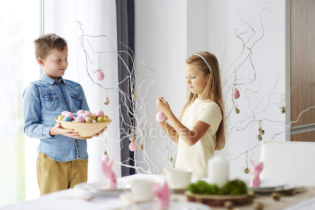 Ragazza e fratello che decorano ramoscelli con uova di Pasqua colorate — Foto stock