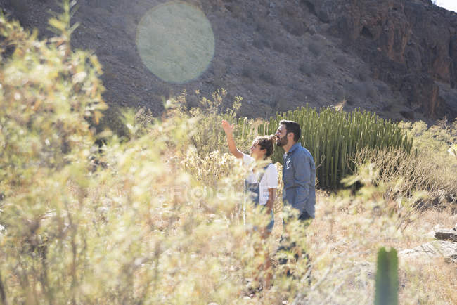 Junges Wanderpaar blickt auf und zeigt auf das sonnenbeschienene Tal, Las Palmas, Kanarische Inseln, Spanien — Stockfoto
