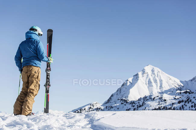Rear view of skier standing in snow and looking at mountains — Stock Photo