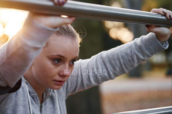 Junge Frau lehnt im Park an Geländer — Stockfoto