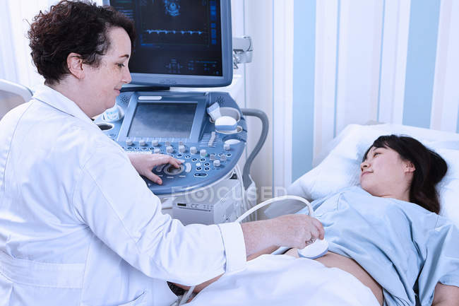 Sonógrafo que da ultrasonido paciente embarazada - foto de stock