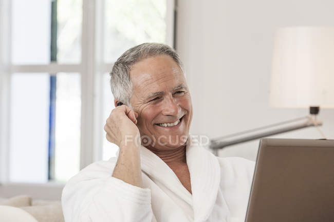 Hombre usando albornoz haciendo una llamada telefónica, sonriendo - foto de stock