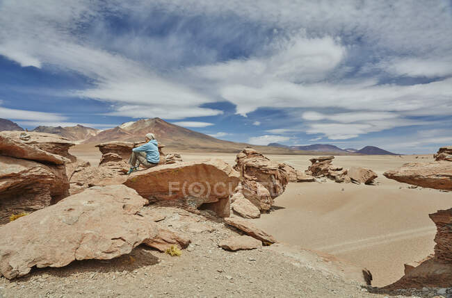 Mujer sentada sobre roca, mirando a la vista, Villa Alota, Potosí, Bolivia, Sudamérica - foto de stock