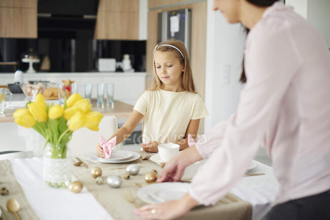 Mädchen und Mutter bereiten Tischdekoration am Ostertisch vor — Stockfoto