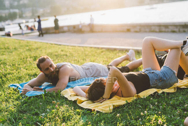 Young couple relaxing on waterfront grass, Lake Como, Lombardy, Italy — Stock Photo