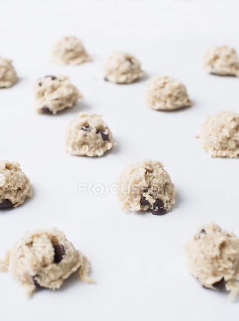 Raw dough balls for chocolate chip cookies isolated on white — Stock Photo
