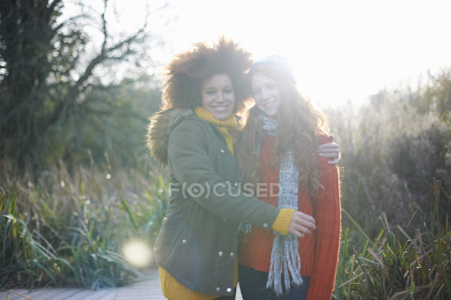Amici femminili che abbracciano e sorridono alla fotocamera — Foto stock