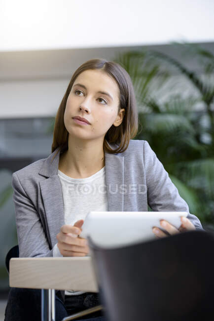 Joven empresaria con portátil en contemplación en el escritorio de la oficina - foto de stock