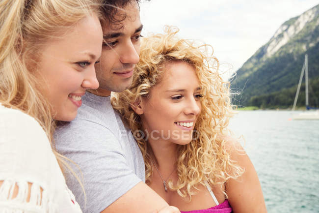 Amigos acurrucados juntos sonriendo, mirando hacia otro lado - foto de stock
