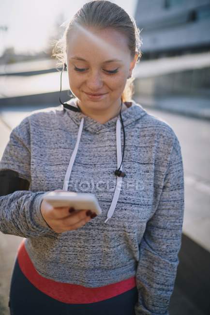 Викривлена молода жінка тренується і дивиться на смартфон — стокове фото
