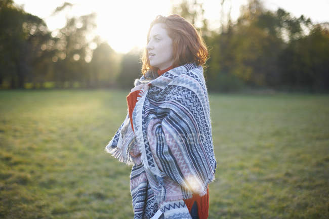 Mujer joven envuelta en manta en un entorno rural - foto de stock
