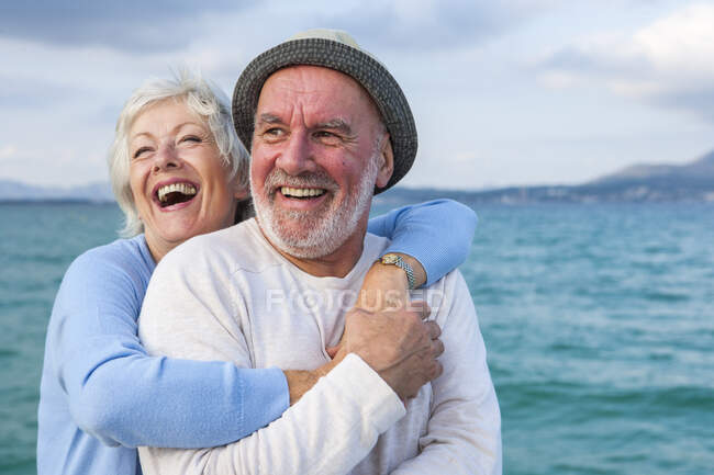 Пара объятий и смех на берегу моря — стоковое фото