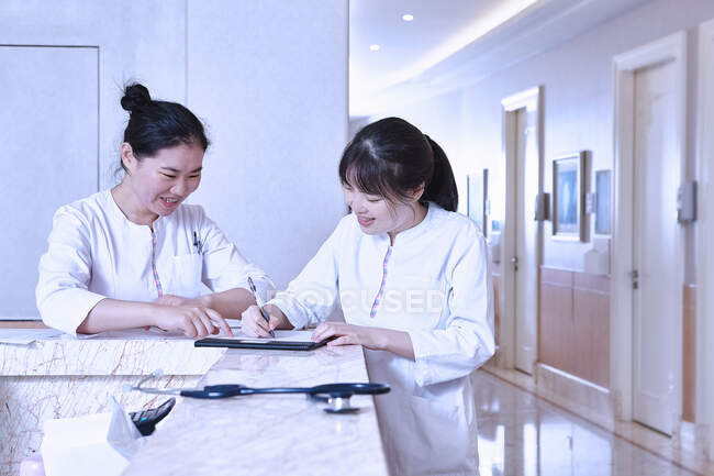 Medical professionals at hospital reception desk using digital tablet — Stock Photo