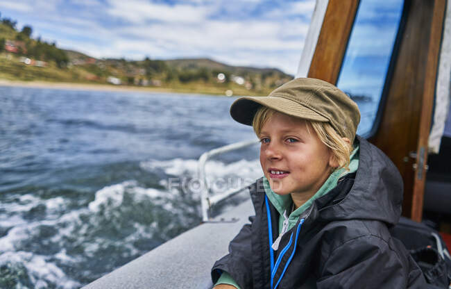 Мальчик, выглядывающий из моторной лодки в море, Пуно, Перу — стоковое фото