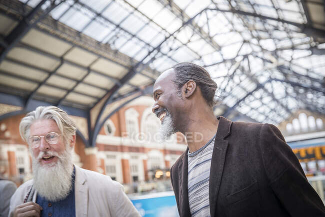 Dos hombres maduros en la estación de tren, caminando juntos - foto de stock