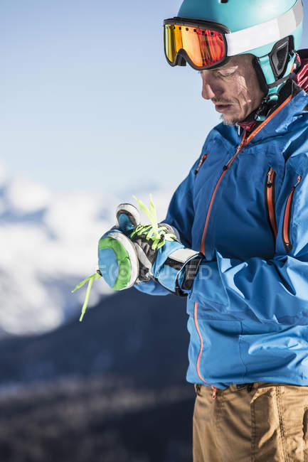 Зрелый мужчина в лыжной одежде надевает лыжные перчатки — стоковое фото