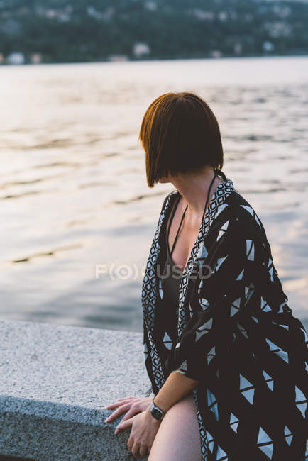 Молодая женщина сидит на набережной на озере Комо, Ломбардия, Италия — стоковое фото