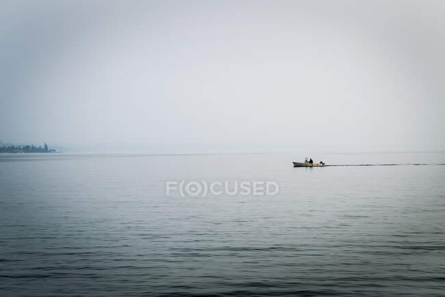 Personas en barco lejano en el lago de Garda, Lazise, Veneto, Italia, Europa - foto de stock