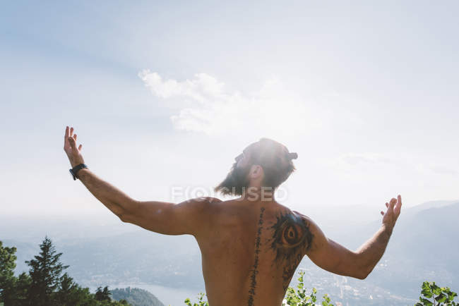 Молодой мужчина с распростертыми объятиями на фоне природы, озеро Комо, Ломбардия, Италия — стоковое фото