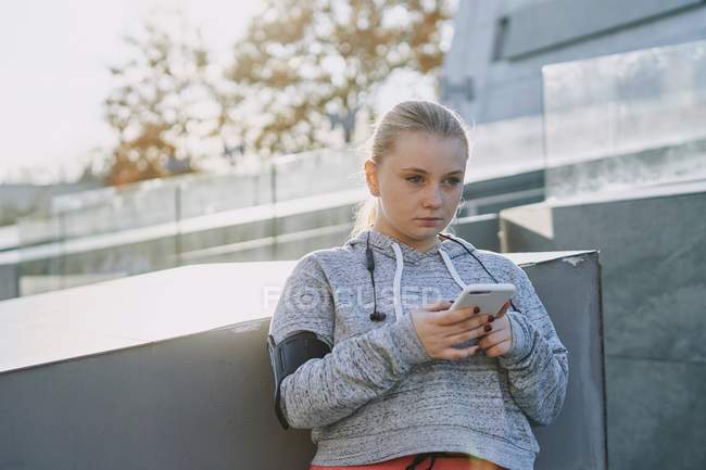 Jovem curvilínea segurando smartphone durante o treinamento — Fotografia de Stock