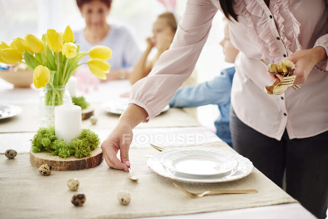 Frau und Familie bereiten Tischdekoration am Ostertisch vor — Stockfoto