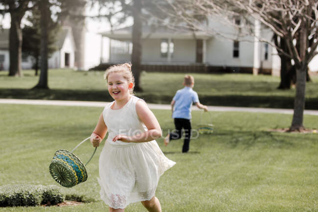 Ragazza e ragazzo all'aperto, tenendo cesti di Pasqua, a caccia di uova di Pasqua — Foto stock