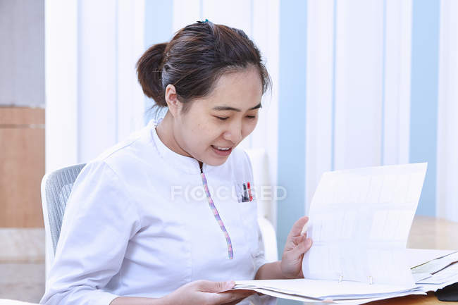 Молодая женщина-врач читает медицинские записи — стоковое фото