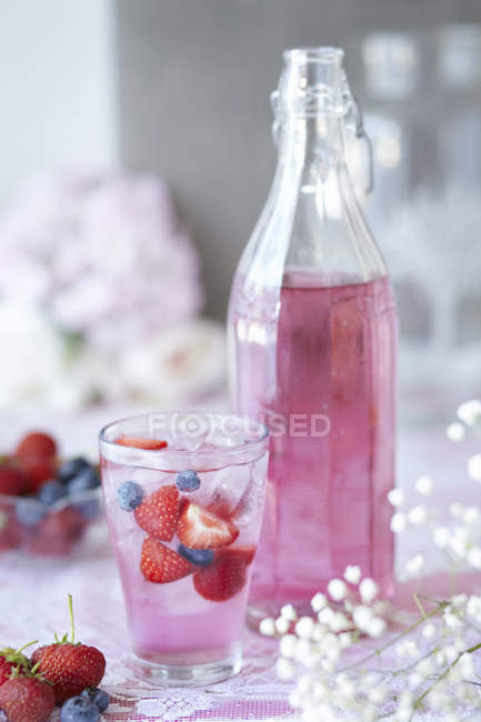 Bicchiere di bacca cordiale con frutta fresca, bottiglia di cordiale accanto al vetro, primo piano — Foto stock