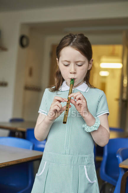 Schoolgirl playing recorder in classroom at primary school — Stock Photo