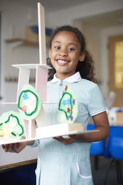Écolière tenant un modèle en carton en classe à l'école primaire, portrait — Photo de stock