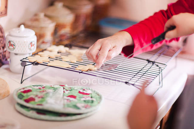 Girl and grandmother placing cookie on baking tray, hands — Stock Photo