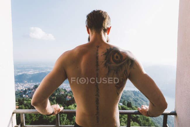 Tatuato giovane uomo guardando giù dalla piattaforma di visualizzazione, Lago di Como, Lombardia, Italia — Foto stock