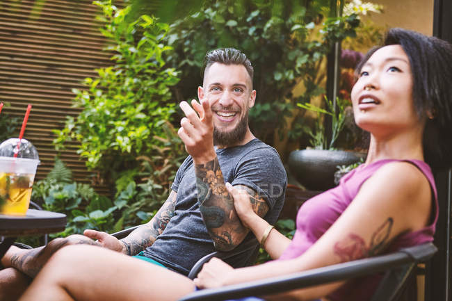 Multi ethnic hipster couple pointing from sidewalk cafe, Shanghai French Concession, Shanghai, China — Stock Photo