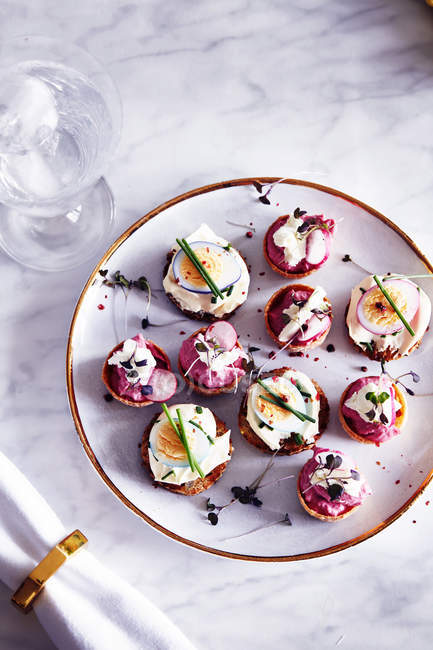 Quails egg and goats cheese canapes on plate, overhead view — Stock Photo