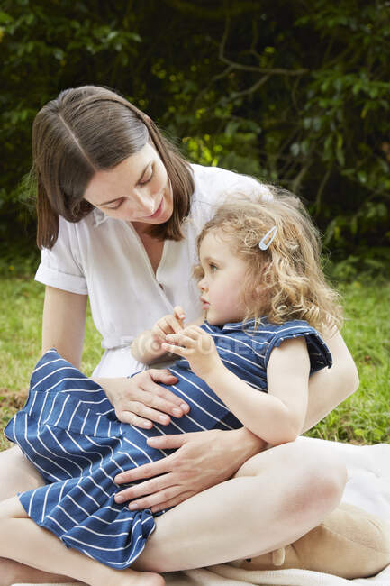 Woman in park with daughter on her lap — Stock Photo