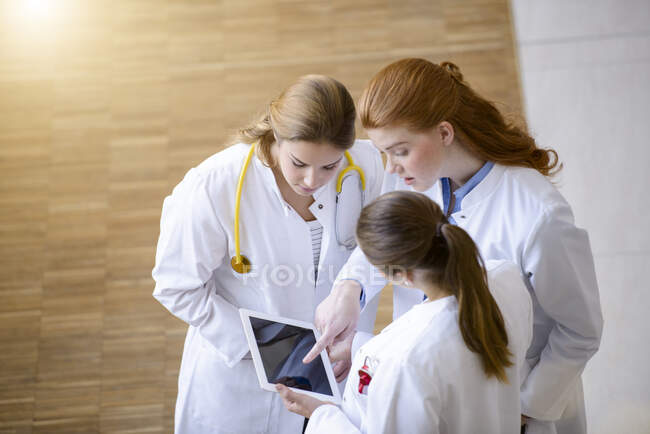 Tres doctores mirando la tableta digital - foto de stock