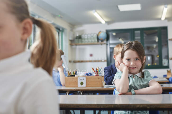 Portrait of schoolgirl sitting at primary school classroom desk — Stock Photo