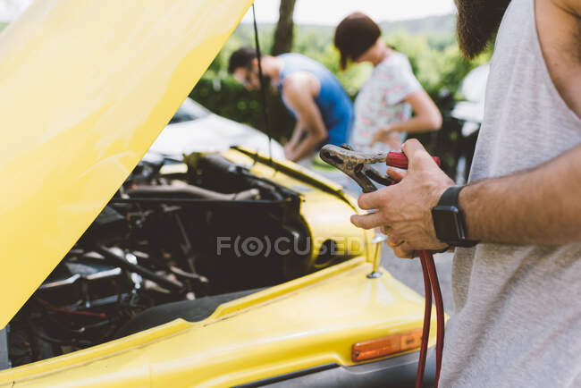 Young adults on road trip using jump leads to start vehicle — Stock Photo